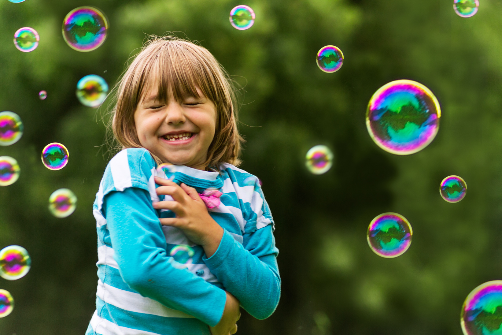 Child in nature playing with bubbles